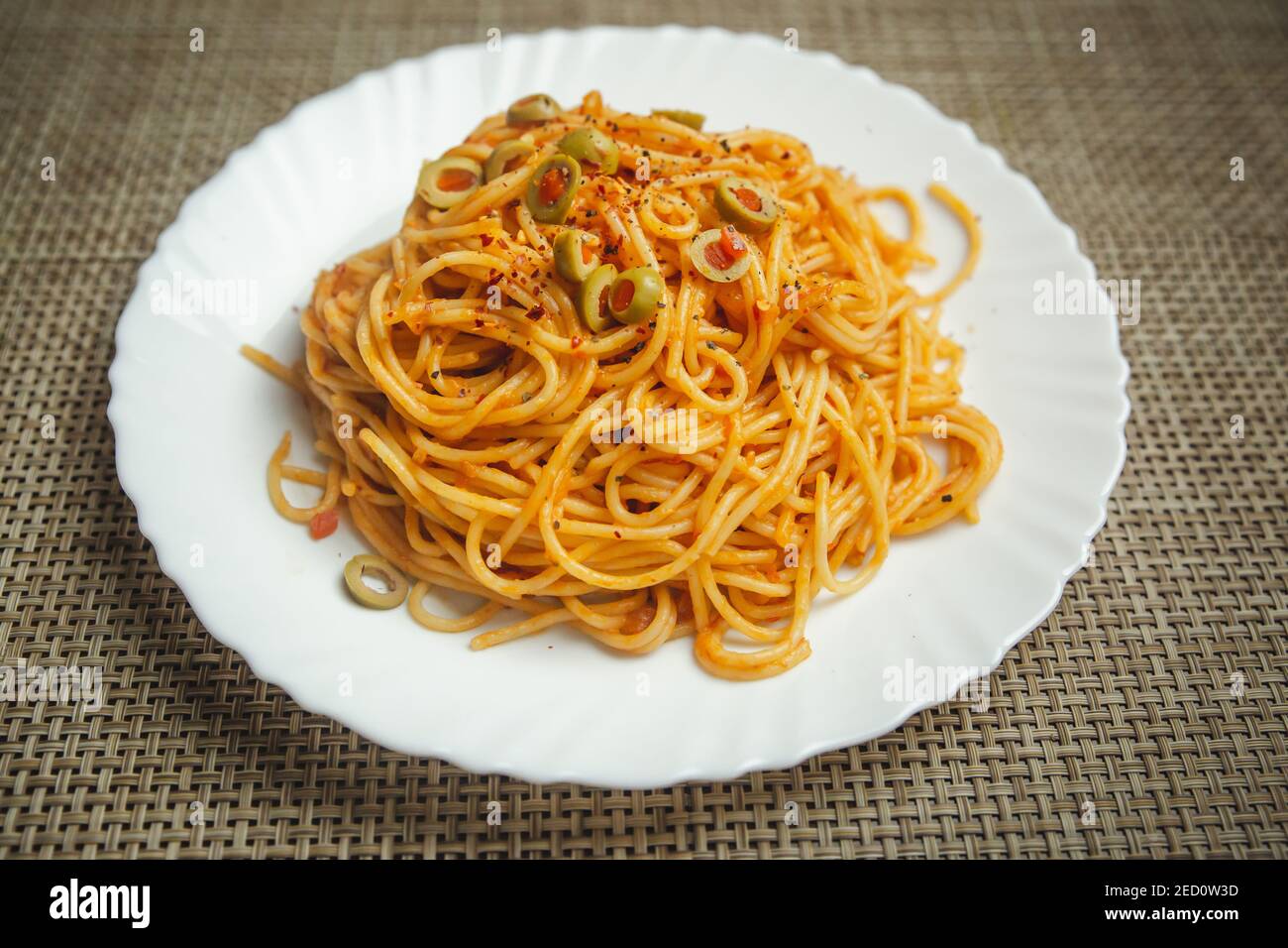 Gustosa e appetitosa pasta italiana di spaghetti con salsa di pomodoro, olive e basilico su piatto. Vista dall'alto, orizzontale Foto Stock