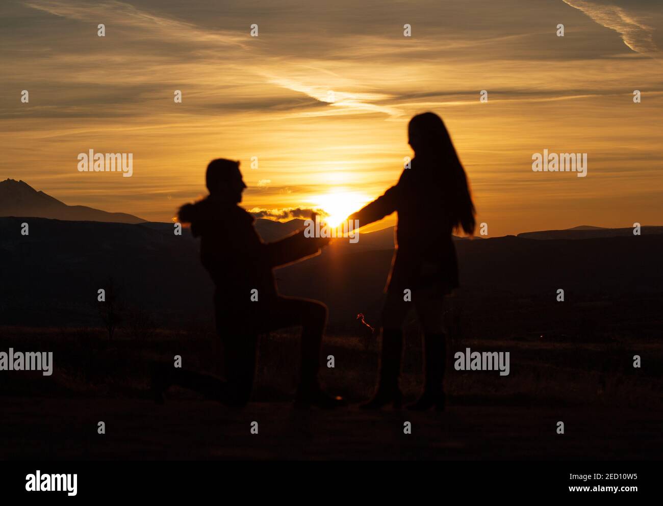 Proposta di matrimonio di una giovane coppia in silhouette durante il tramonto in Cappadocia. Il sole sorge frım anello di diamante Foto Stock