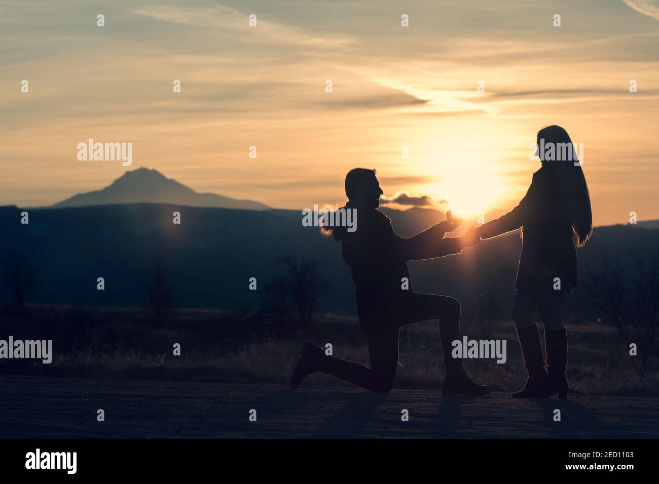 Proposta di matrimonio di una giovane coppia in silhouette durante il tramonto in Cappadocia. Il sole sorge frım anello di diamante Foto Stock