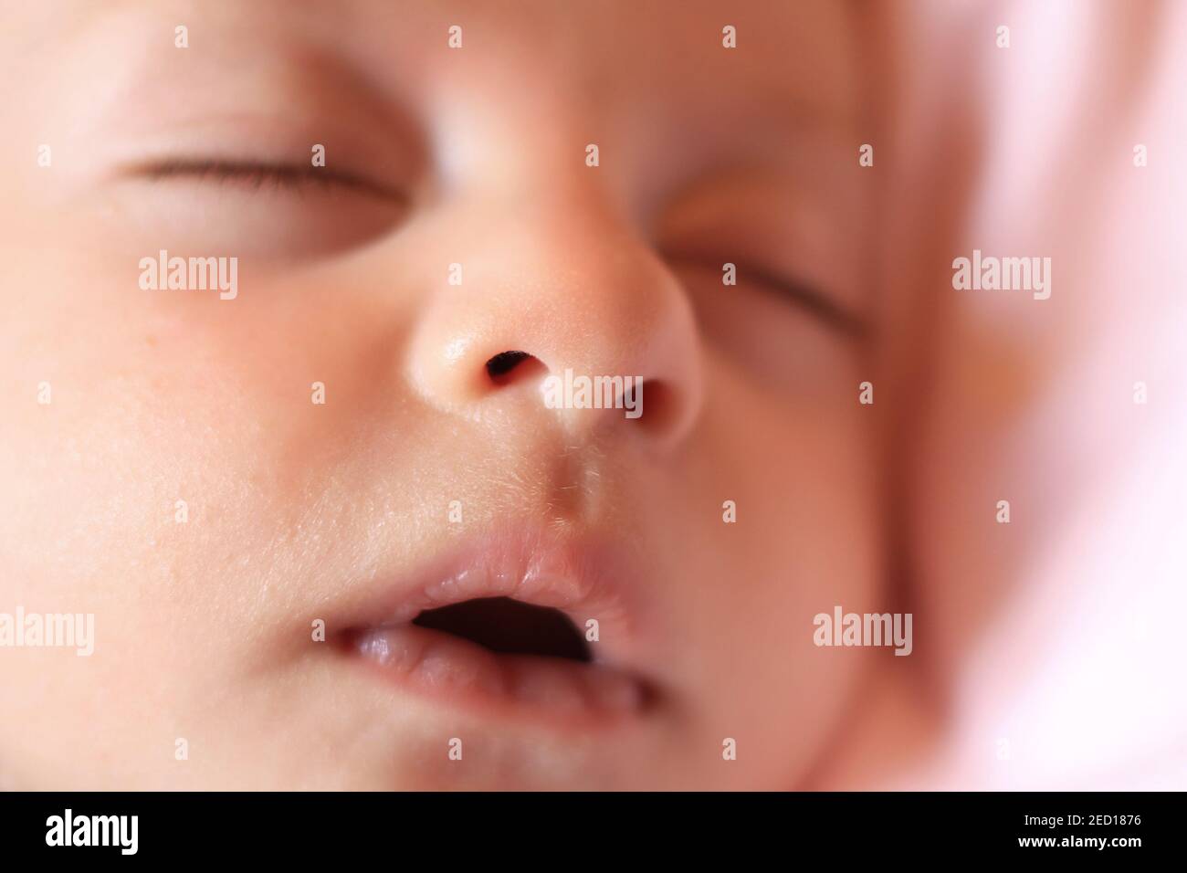 Un primo piano del viso di un neonato che dorme pacificamente con una bocca aperta. Foto Stock