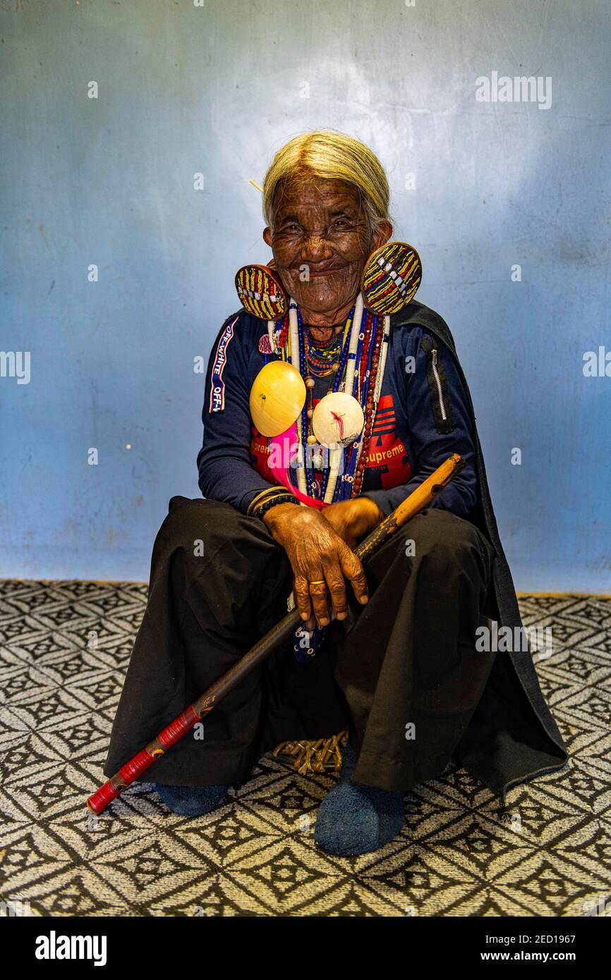 Chin Kaang Hill-tribù donna con tatuaggio facciale tradizionale e elaborati orecchini tribali che giocano un flauto con il naso, Mindat, Chin stato, Myanmar Foto Stock