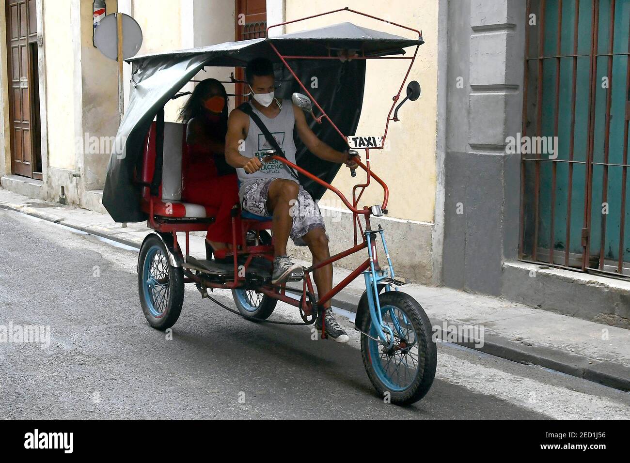 L'Avana, Cuba. 12 Feb 2021. Una donna prende un giro in un triciclo privatamente posseduto per affitto a l'Avana, Cuba, 12 febbraio 2021. A seguito delle nuove misure approvate nel corso di una riunione del Consiglio dei ministri di Cuba la settimana scorsa, l'elenco delle attività in cui sono impegnati gli imprenditori privati locali è stato esteso dal 127 a più di 2,000. Credit: Joaquin Hernandez/Xinhua/Alamy Live News Foto Stock