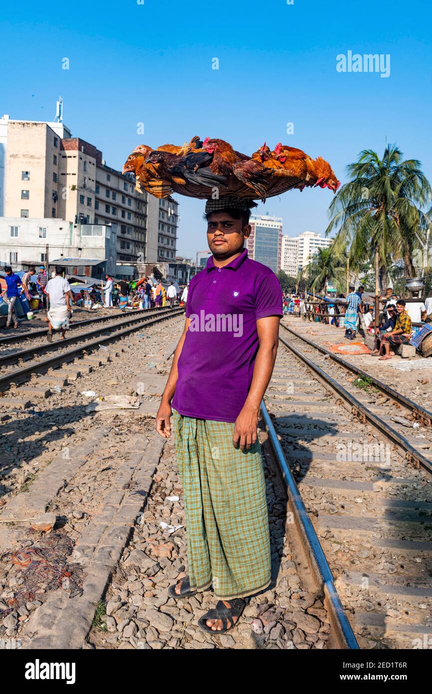 Venditore di strada sulle piste ferroviarie che attraversano Kawran Bazar, Dhaka, Bangladesh Foto Stock