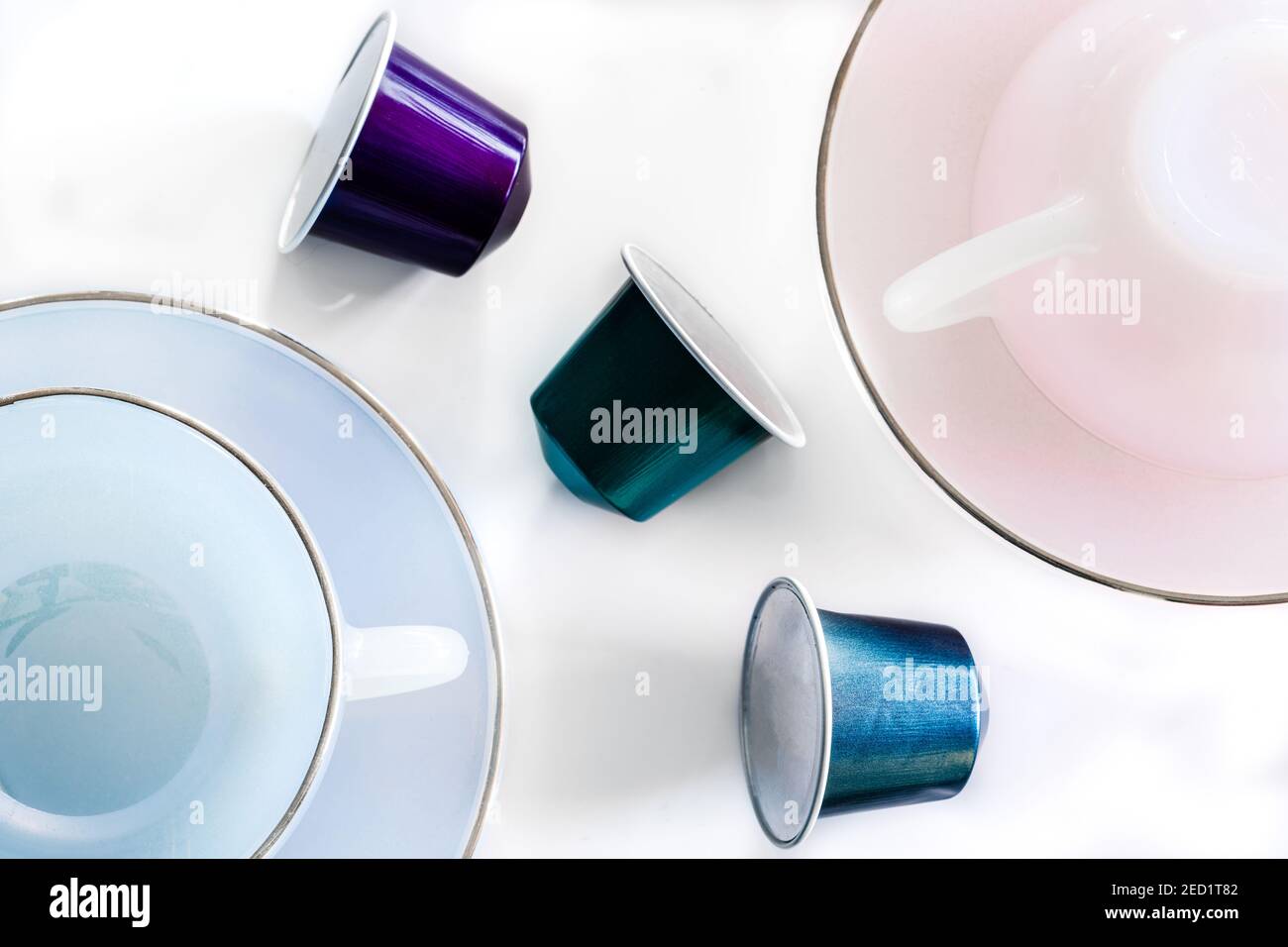 Vista dall'alto della raccolta delle cialde di caffè poste vicino a vuoto tazza e piattino in ceramica su sfondo bianco Foto Stock