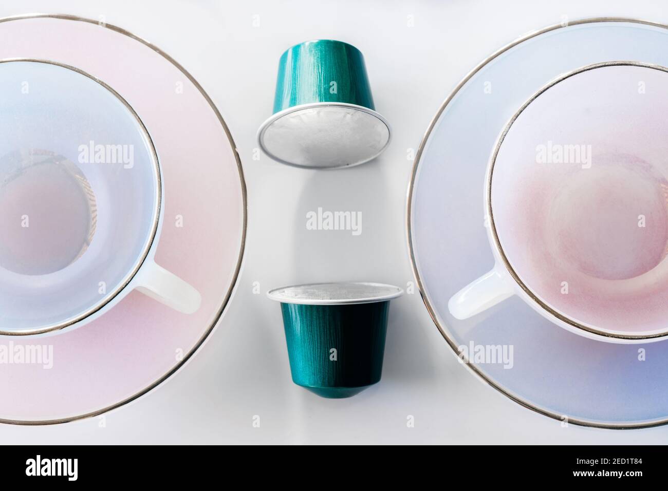 Vista dall'alto della raccolta delle cialde di caffè poste vicino a vuoto tazza e piattino in ceramica su sfondo bianco Foto Stock
