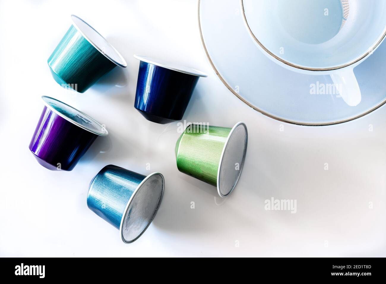 Vista dall'alto della raccolta delle cialde di caffè poste vicino a vuoto tazza e piattino in ceramica su sfondo bianco Foto Stock