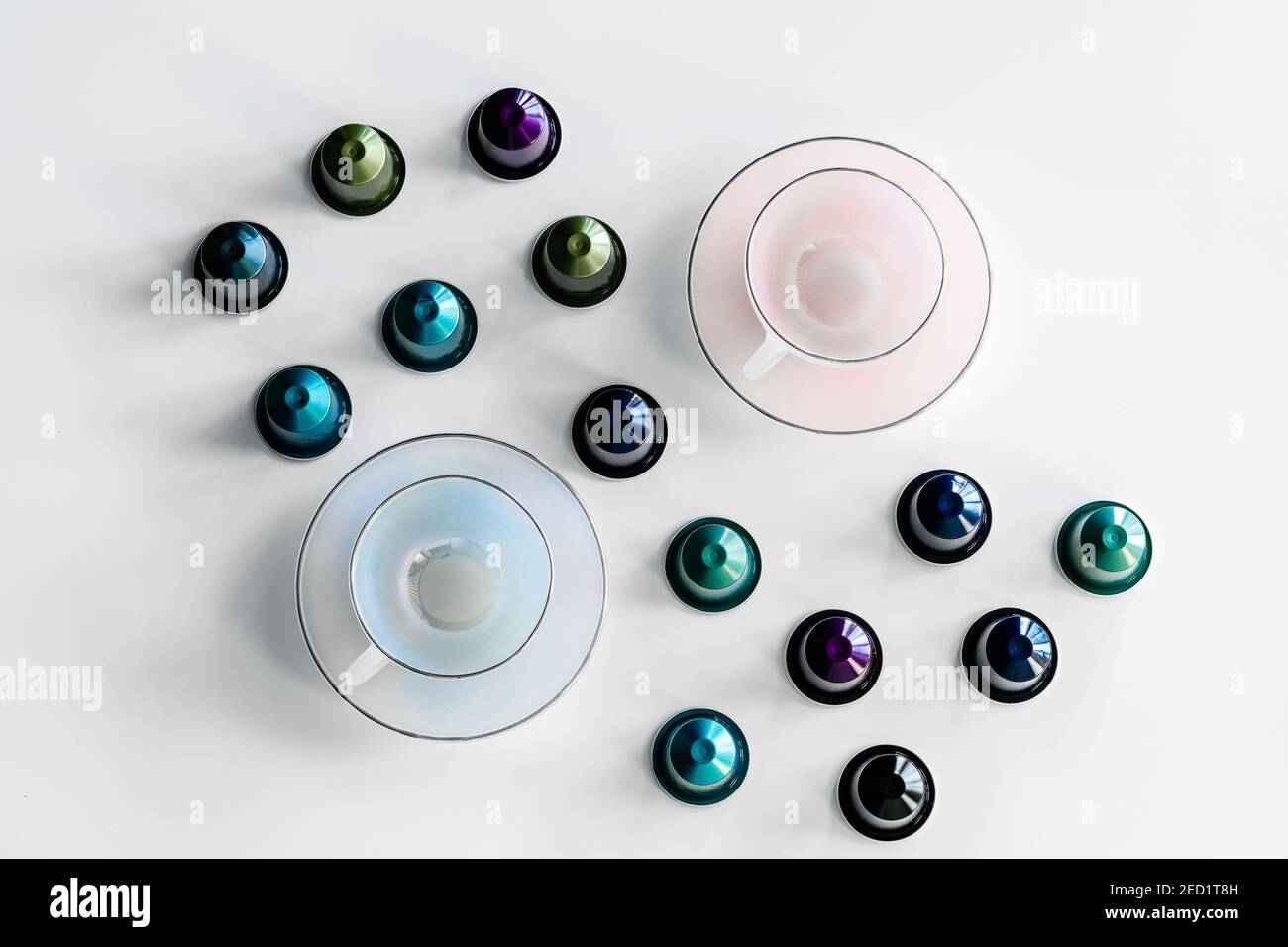 Vista dall'alto della raccolta delle cialde di caffè poste vicino a vuoto tazza e piattino in ceramica su sfondo bianco Foto Stock