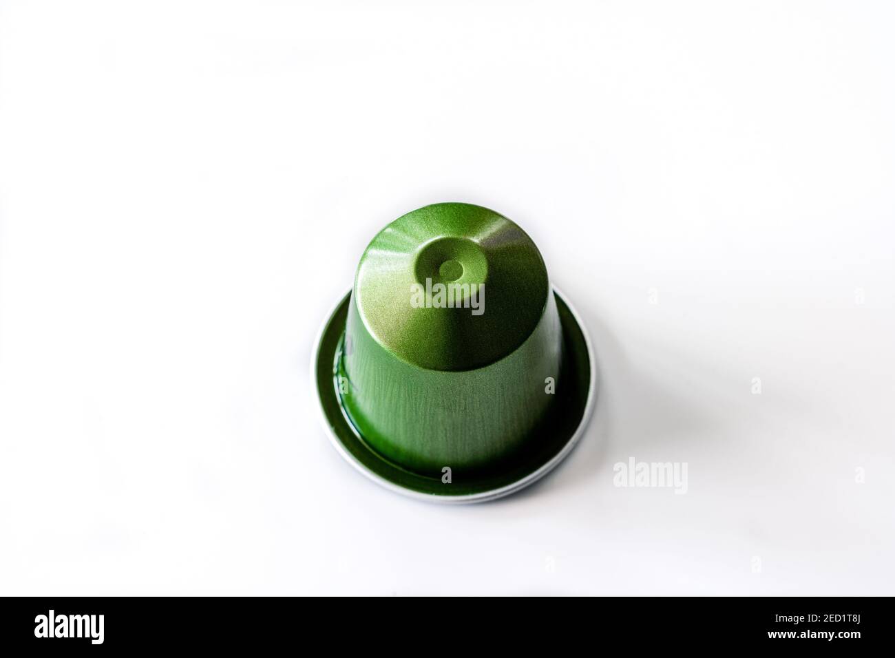 Dall'alto, la cialda di caffè verde in metallo è posizionata sopra sfondo bianco in studio Foto Stock