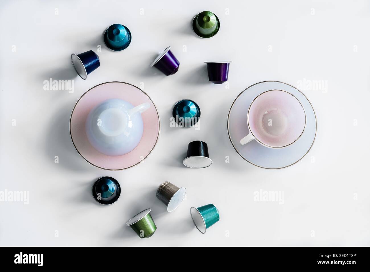 Vista dall'alto della raccolta delle cialde di caffè poste vicino a vuoto tazza e piattino in ceramica su sfondo bianco Foto Stock