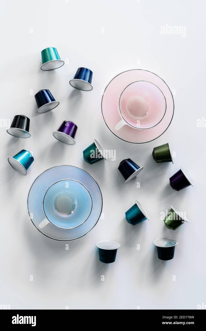 Vista dall'alto della raccolta delle cialde di caffè poste vicino a vuoto tazza e piattino in ceramica su sfondo bianco Foto Stock