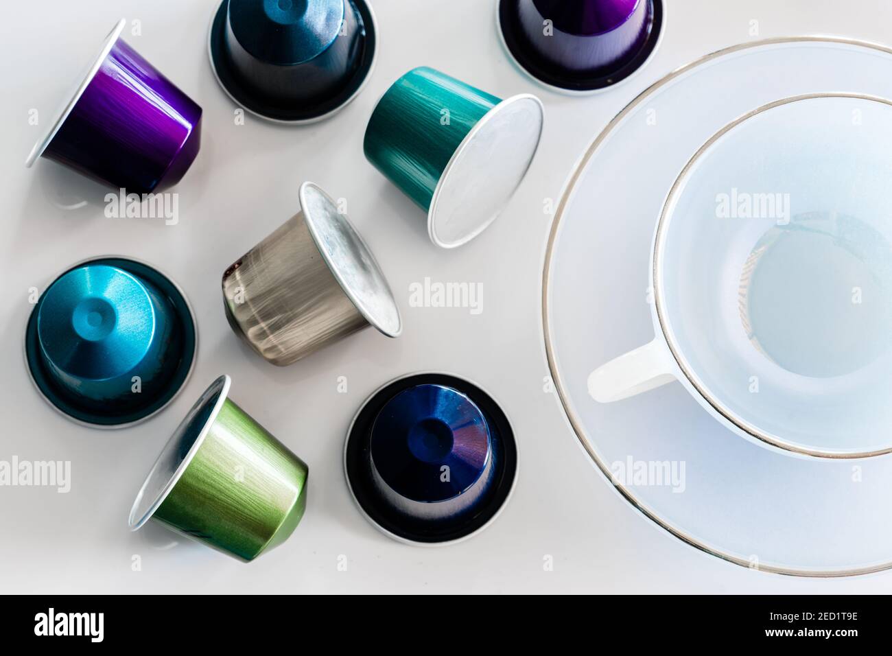 Vista dall'alto della raccolta delle cialde di caffè poste vicino a vuoto tazza e piattino in ceramica su sfondo bianco Foto Stock