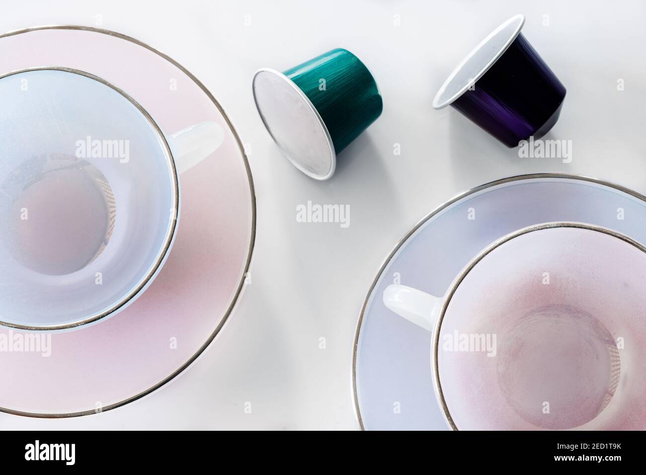 Vista dall'alto della raccolta delle cialde di caffè poste vicino a vuoto tazza e piattino in ceramica su sfondo bianco Foto Stock