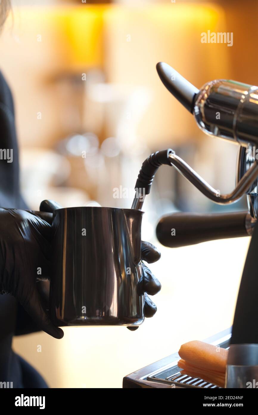 barista mani che fumano il latte per il caffè nella moderna macchina da caffè, primo piano Foto Stock