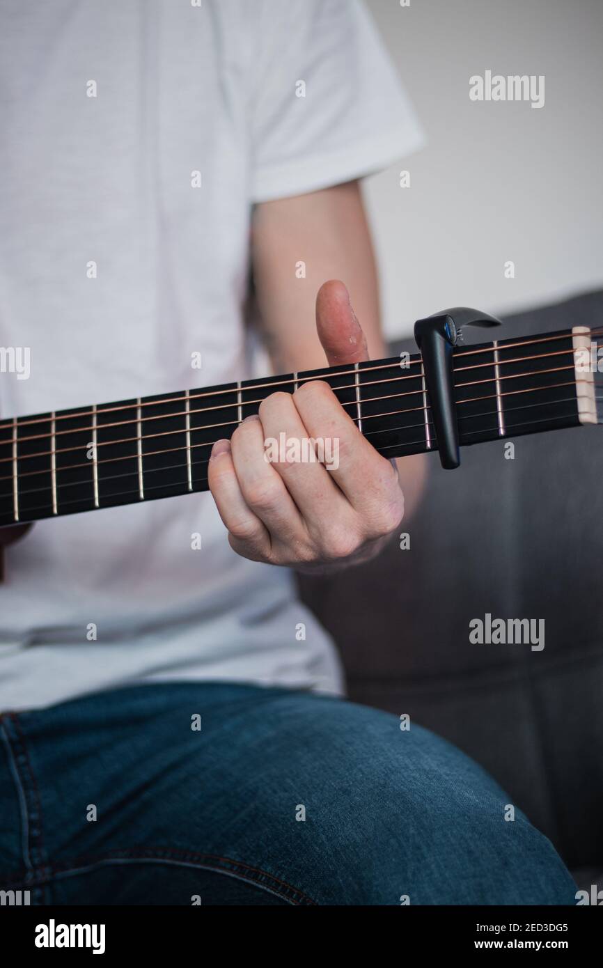 parte di una chitarra di legno e la mano di un cantante che cambia tenendo  la