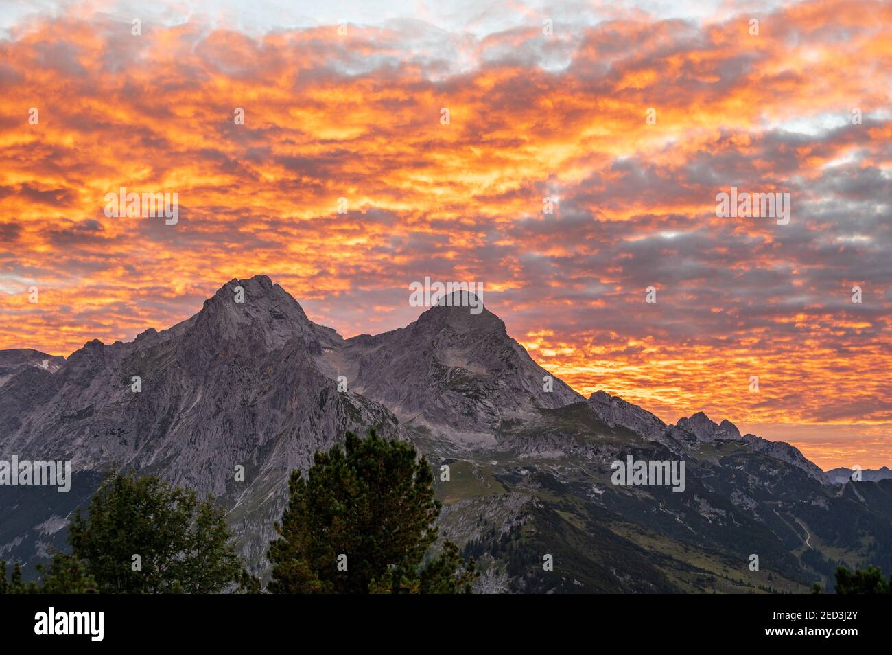 Le nuvole arancioni dopo il tramonto nelle alpi sembrano Cielo è sul fuoco con vista sulle montagne Alpsitze e. Hochblassen Foto Stock