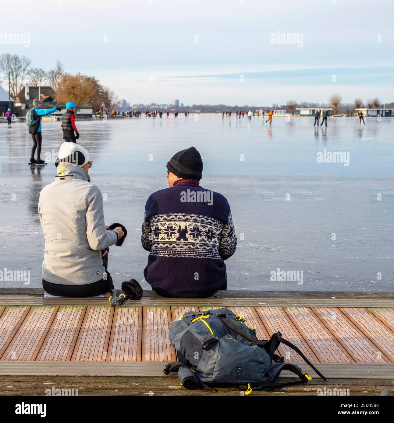 Pattinatori di ghiaccio che hanno una pausa su un molo di legno con vista su Vennemeer, Warmond, Kaag & Braasem, Sud Olanda, Paesi Bassi. Foto Stock