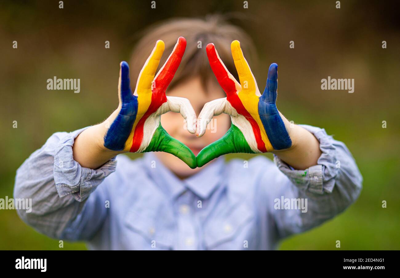 Mani di capretto dipinte in Seychelles bandiera colore mostra simbolo di il cuore e il gesto d'amore sullo sfondo della natura Foto Stock