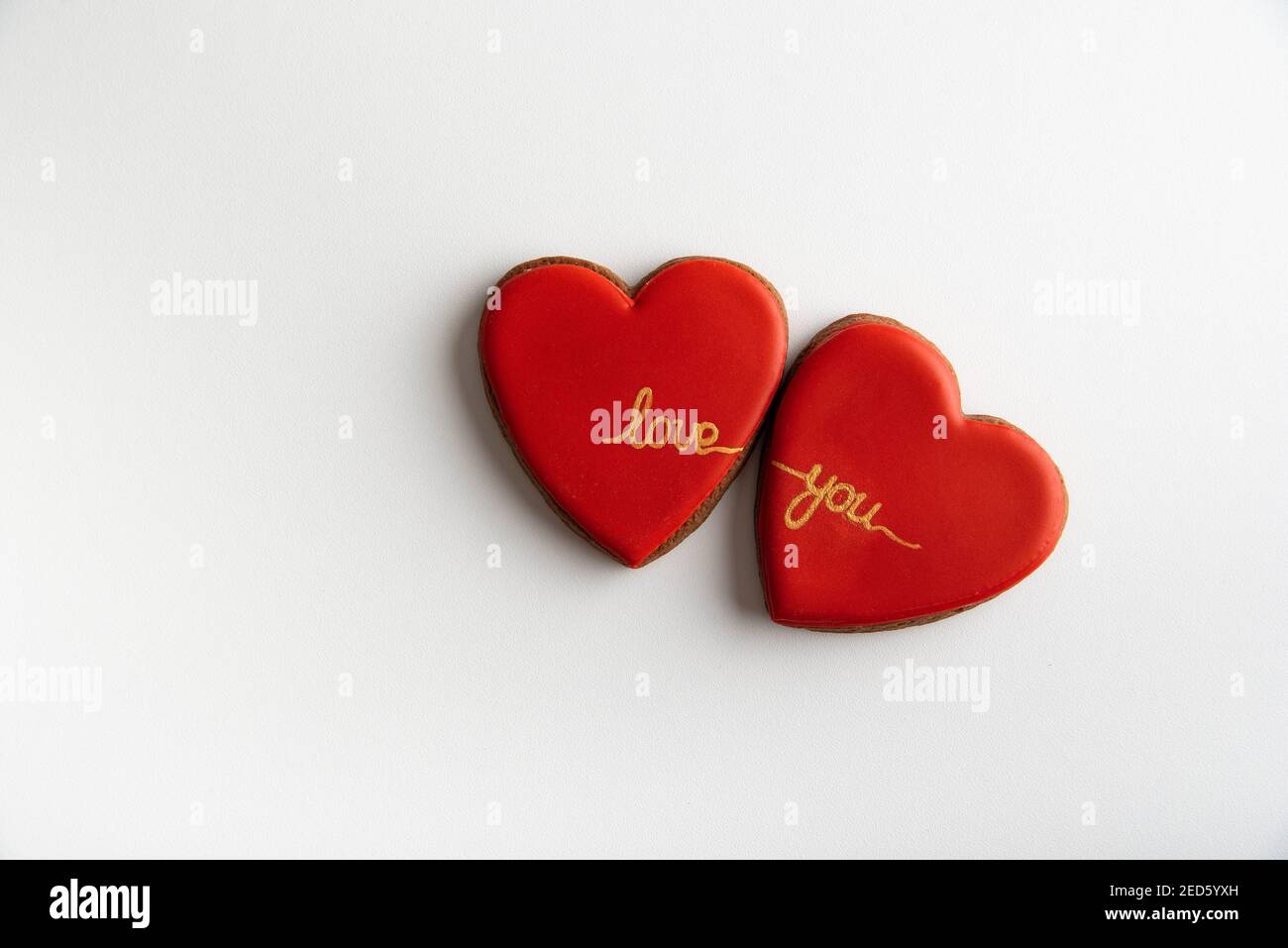Due cuori rossi con le parole vi amano su sfondo bianco vista dall'alto. San Valentino. Foto Stock