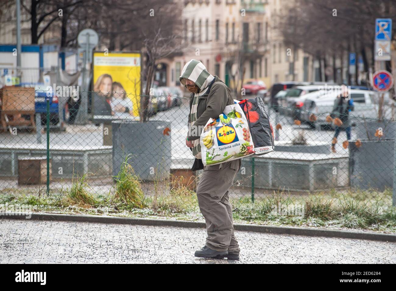 Praga, Repubblica Ceca. 02-13-2021. Un uomo senza casa sta camminando portando tutte le sue borse nel centro della città di Praga durante una fredda giornata invernale. Foto Stock