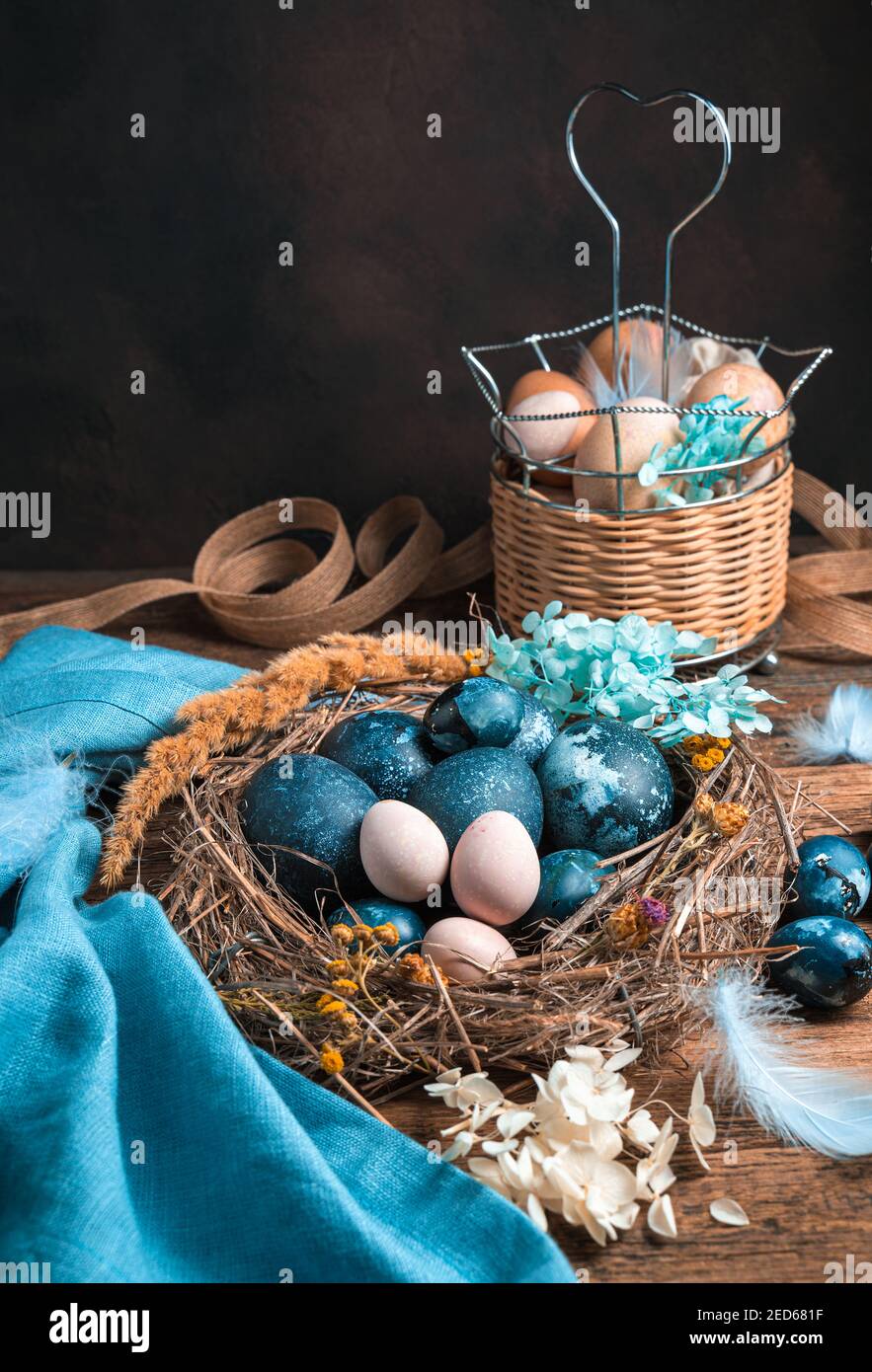 Uova di pollo e quaglia in un nido e in un cestino su sfondo marrone. Foto Stock