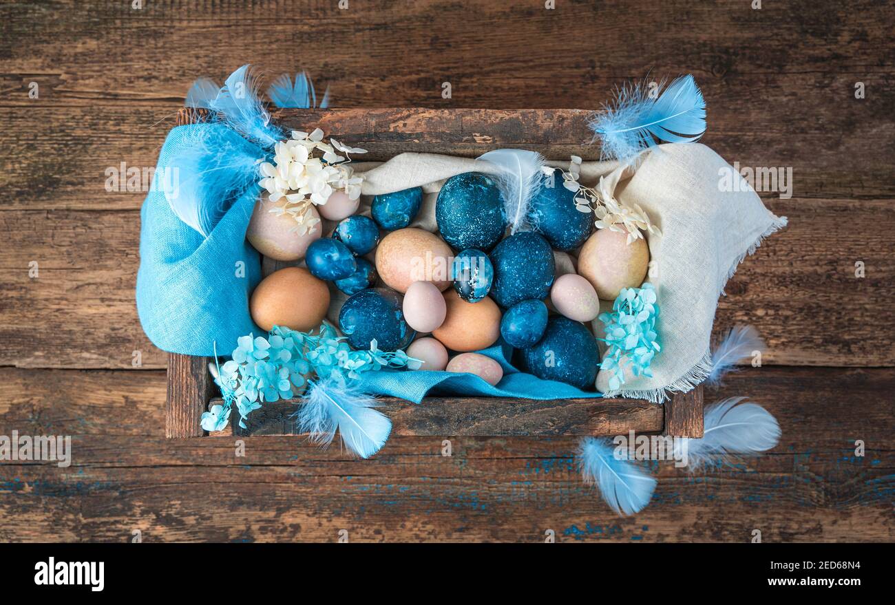 Una scatola con uova di Pasqua in blu e colori naturali su sfondo ligneo. Foto Stock