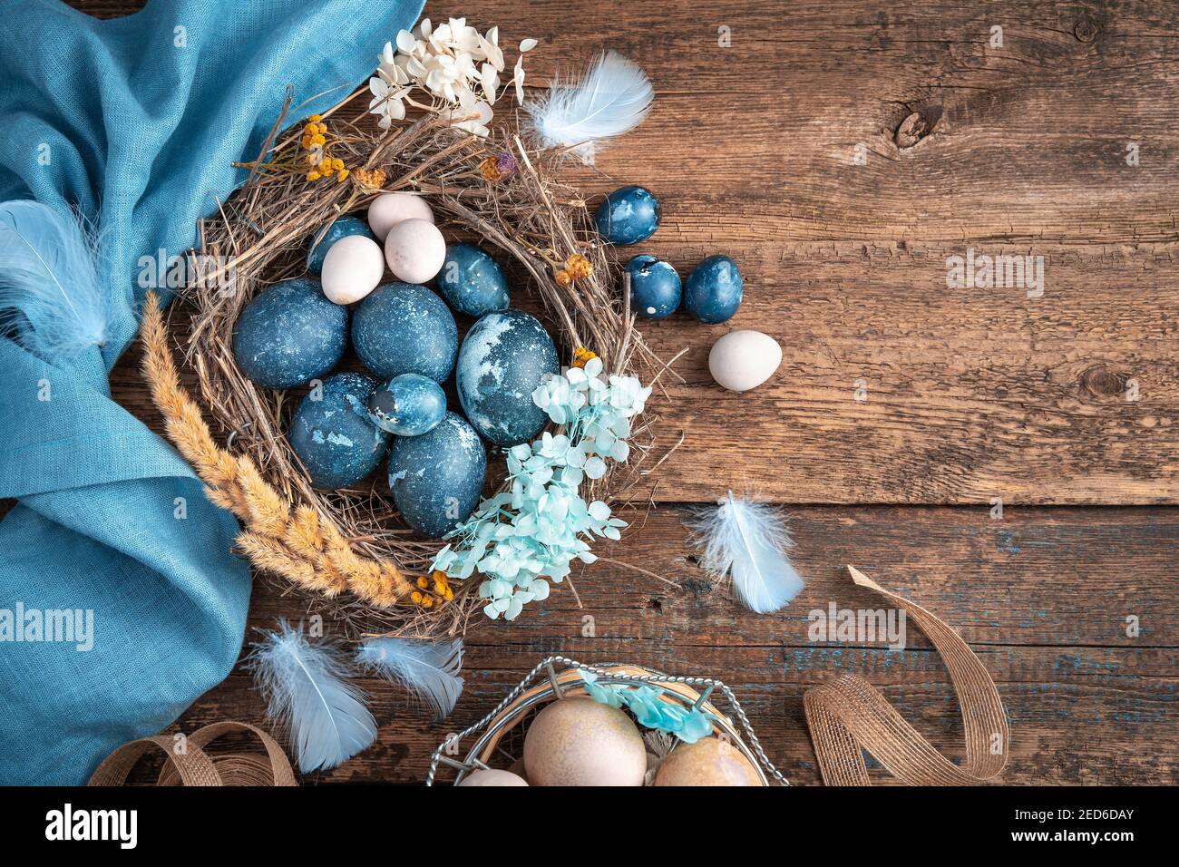 Una bella composizione pasquale con uova colorate di diversi tipi in un nido d'uccello. Foto Stock