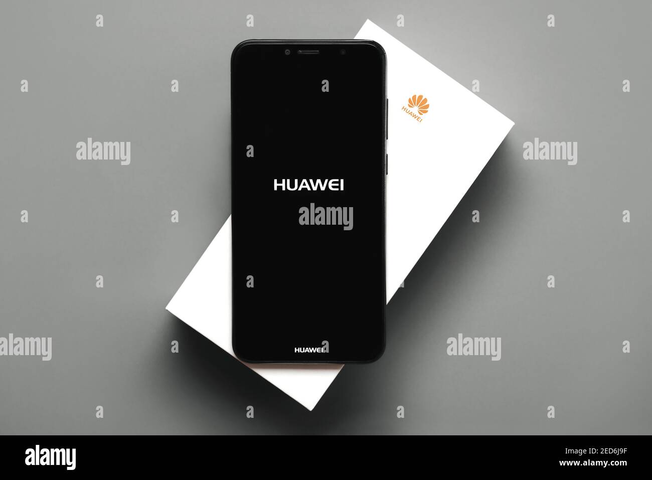 Logo Huawei sullo schermo nero dello smartphone sopra la sua casella bianca su sfondo grigio Foto Stock