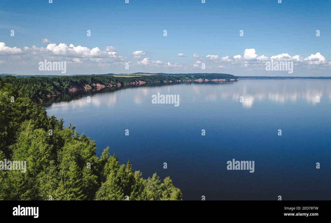 Tranquillo paesaggio di lago blu con nuvole, litorale boscoso Foto Stock
