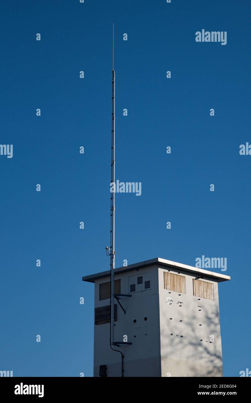 Atmosfera fresca in una mattinata soleggiata con cielo blu come i segnali vengono trasmessi attraverso la campagna da un'antenna di comunicazione su una casa torre. Foto Stock