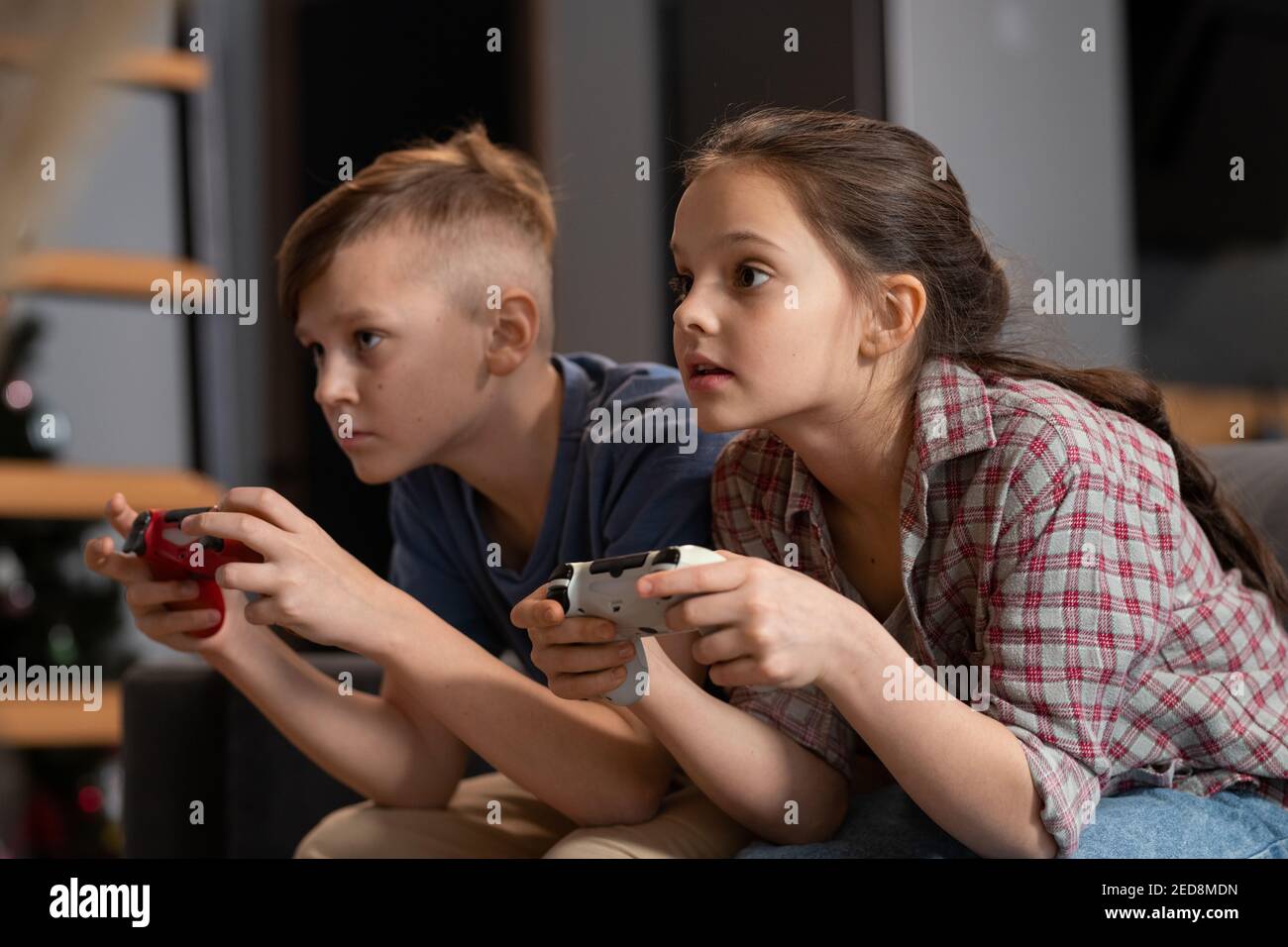Due simpatici fratelli che siedono sul divano di fronte tv e gioco video in salotto durante le vacanze o nel fine settimana Foto Stock