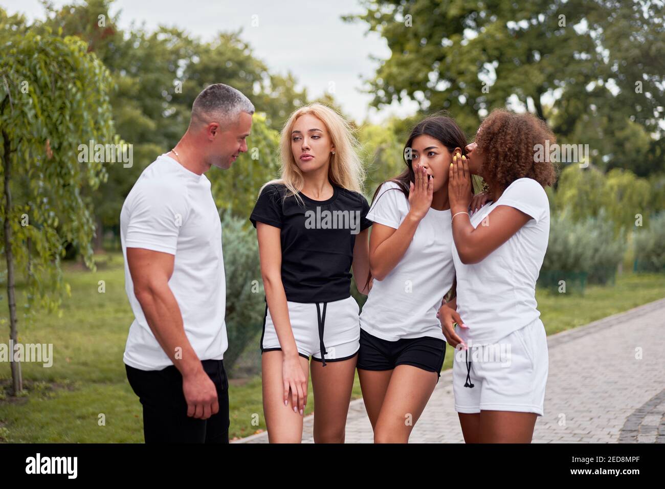 Amici adolescenti di gruppo multietnico. afroamericano asiatico caucasico studente passare il tempo insieme amicizia multirazziale felice sorridente persone vestito bianco nero sportswear incontro all'aperto Foto Stock