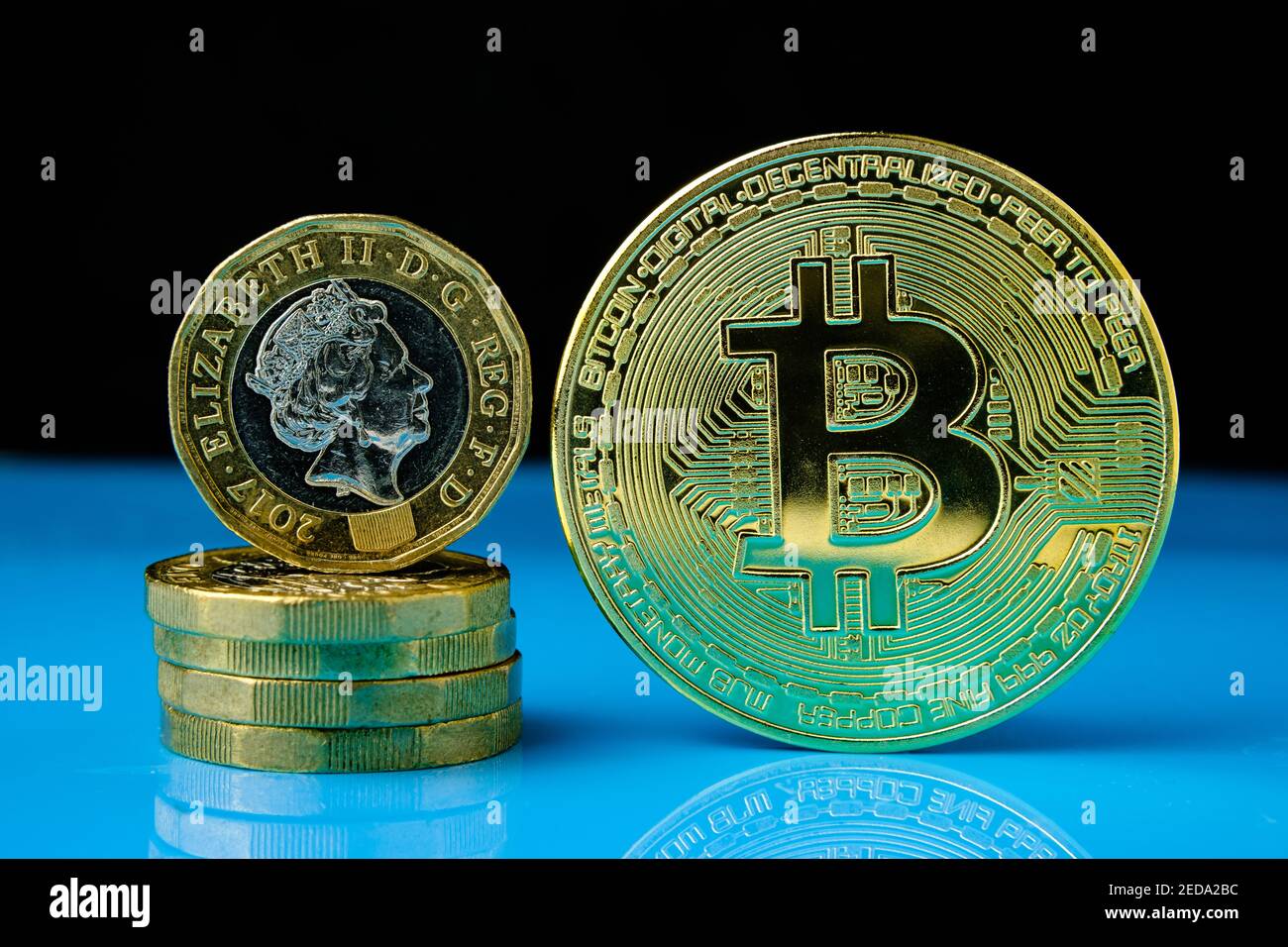 Bitcoin e monete inglesi da una libbra hanno messo il tocetere sulla superficie riflettente con sfondo sfocato. Concetto di criptovaluta rispetto alla curra tradizionale Foto Stock