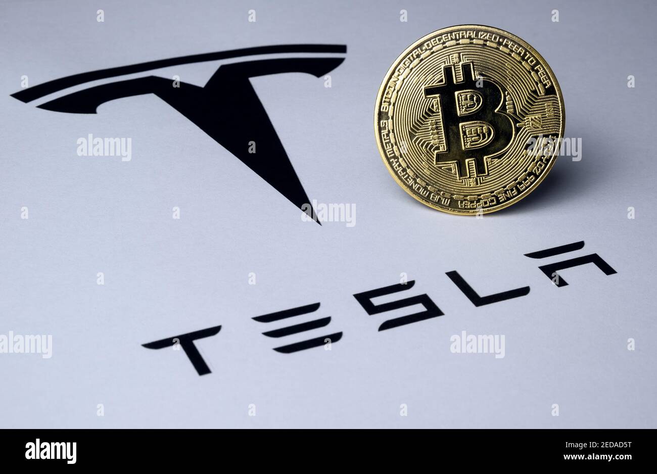 Bitcoin e il logo Tesla sono visualizzati su un documento cartaceo. Concetto di investimento nella criptovaluta. Messa a fuoco selettiva. Foto Stock