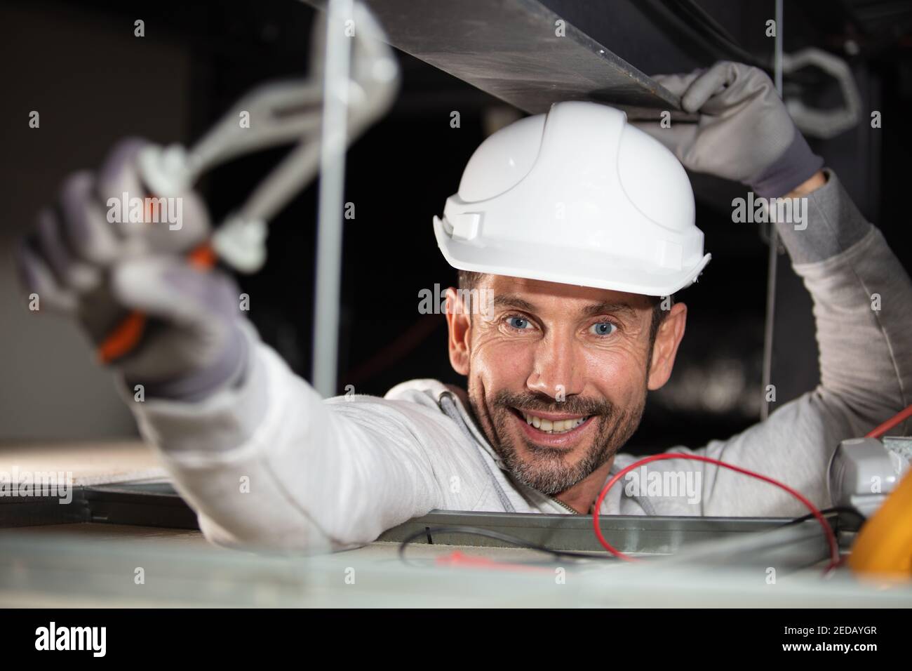 operatore che installa i cavi all'interno dei condotti dell'aria Foto Stock