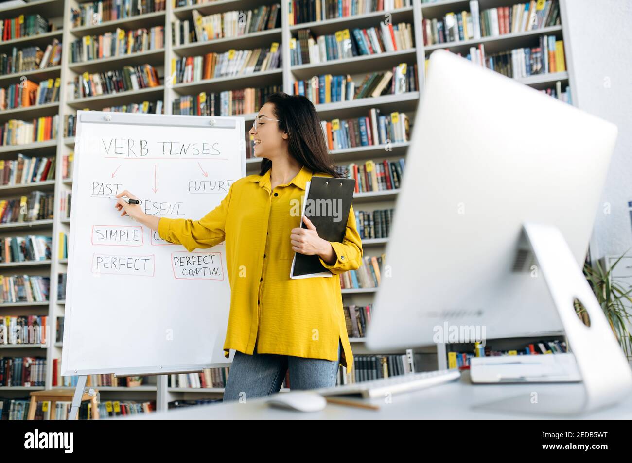 Lezione online, apprendimento a distanza. Una giovane insegnante di sesso femminile intelligente conduce una lezione o un webinar online per gli studenti tramite una videoconferenza che mostra le informazioni sulla lavagna a fogli mobili Foto Stock