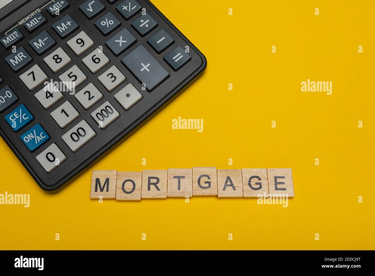 Frase o parola - ipoteca. Blocco di legno parola lettera e moderna calcolatrice su sfondo giallo, business concept con spazio per il testo Foto Stock
