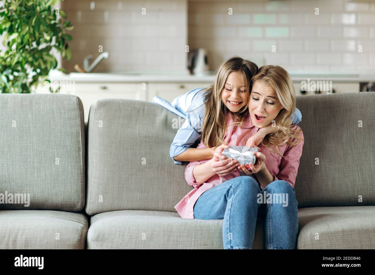 Mamma felice con sua figlia. Bella figlia ha dato alla sua amata madre un regalo per il giorno o il compleanno della madre. Sorpresa per la madre Foto Stock