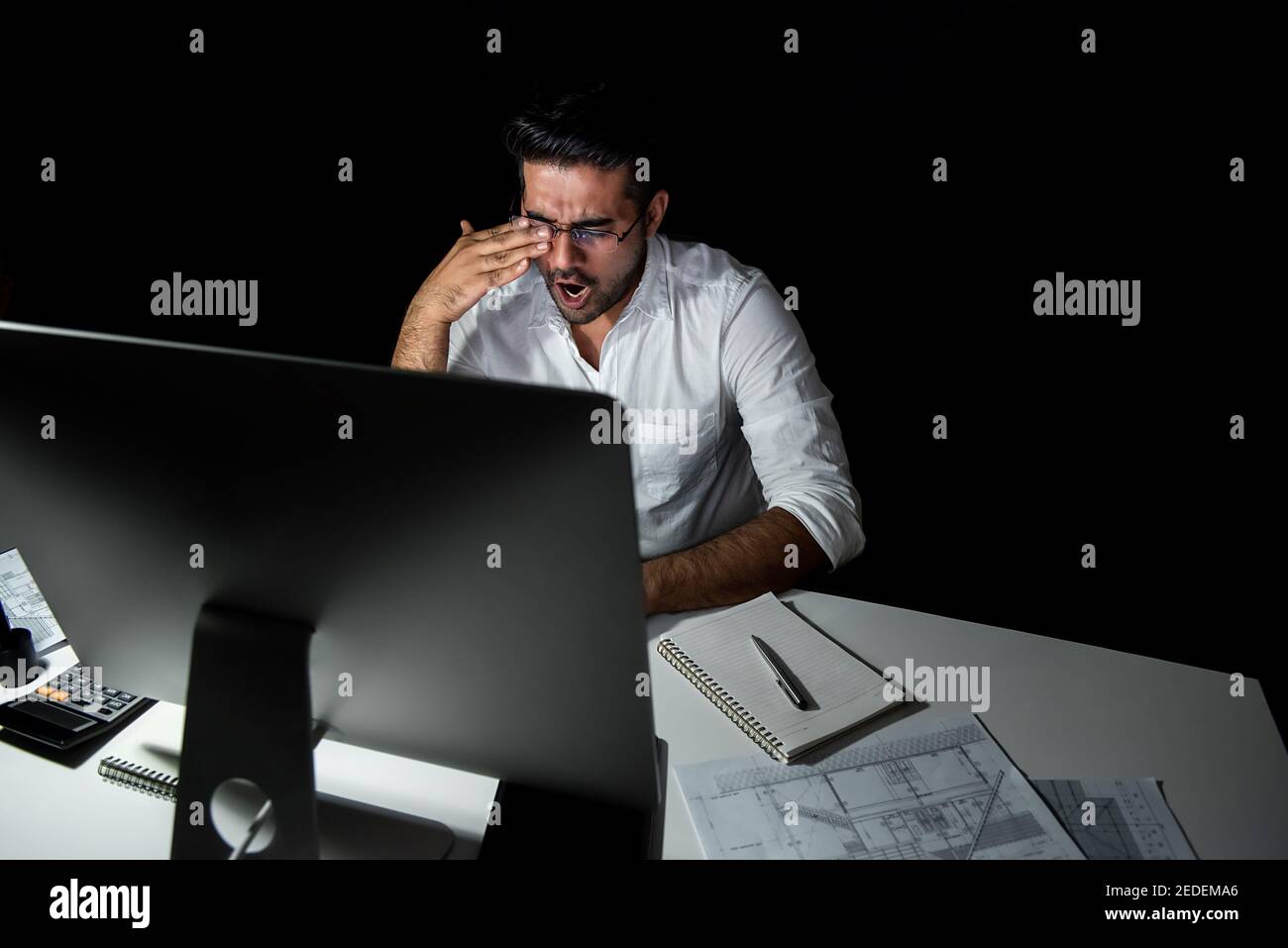 Stanco uomo d'affari asiatico stanco che si sente sonnolento e sbadigliato mentre lavora turno notturno davanti al computer Foto Stock
