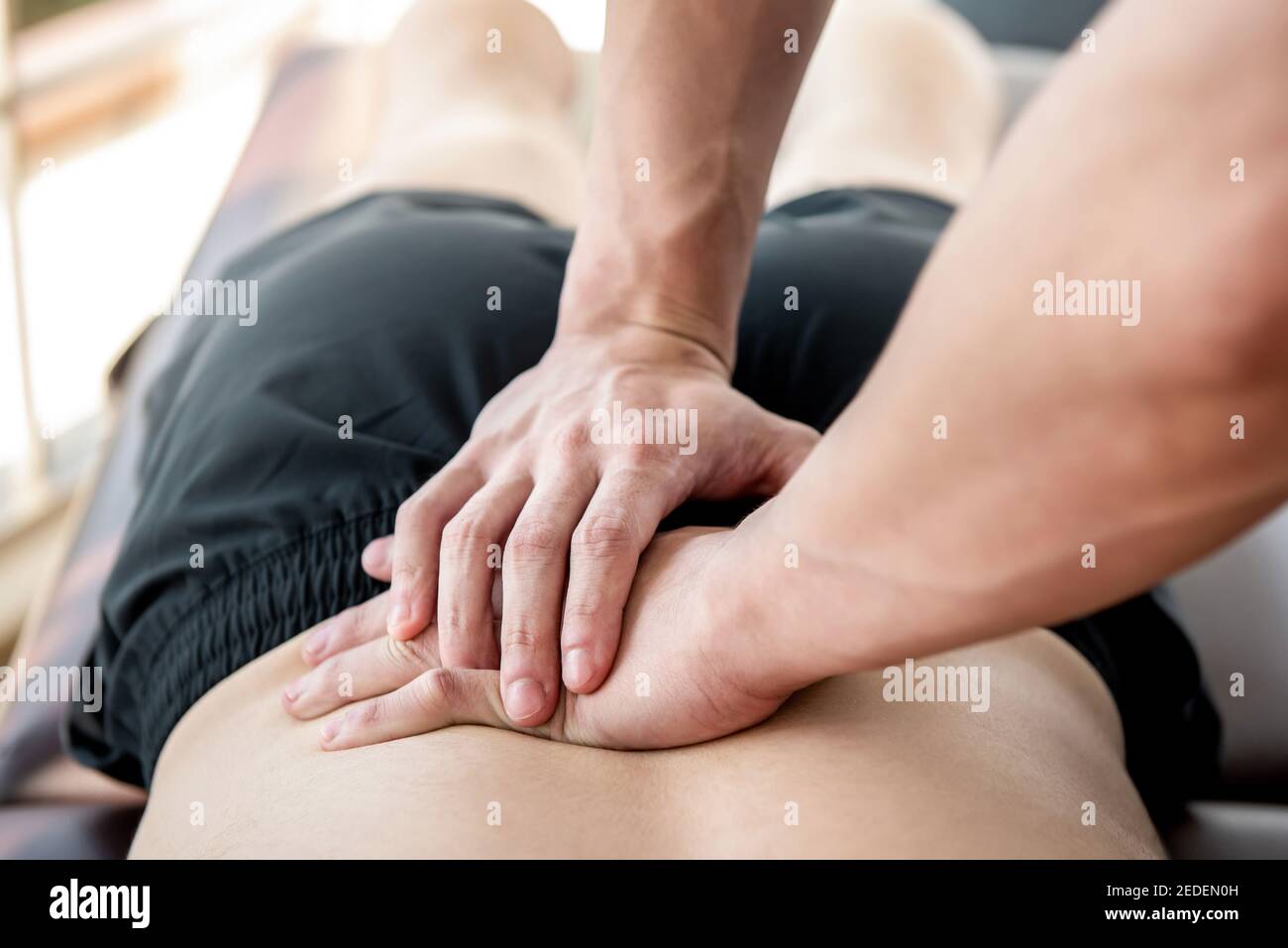 Terapeuta che dà massaggio di sport della schiena più bassa al paziente maschile dell'atleta in clinica Foto Stock