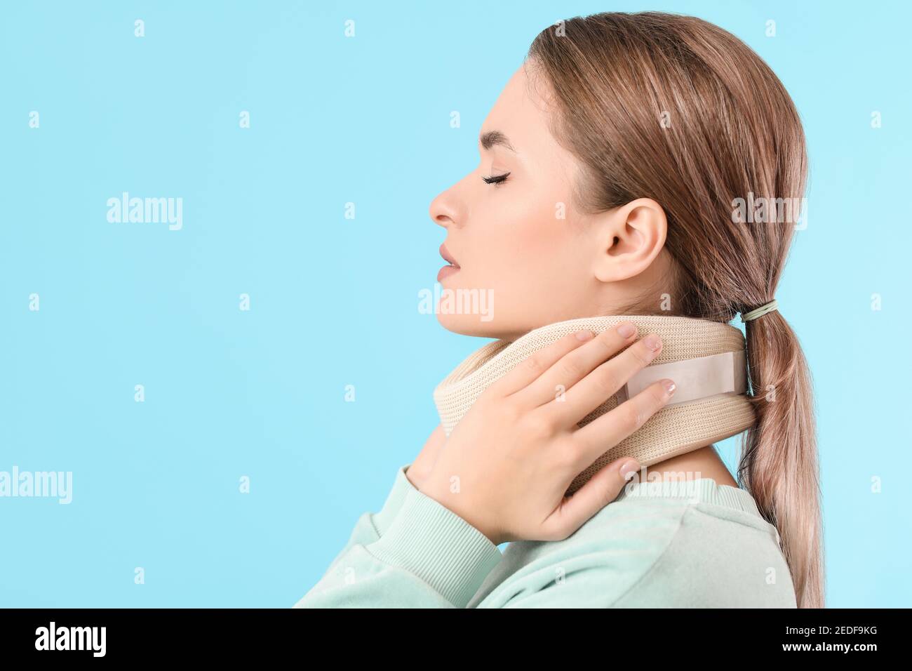 Giovane donna con collare cervicale sul collo contro sfondo colorato Foto Stock