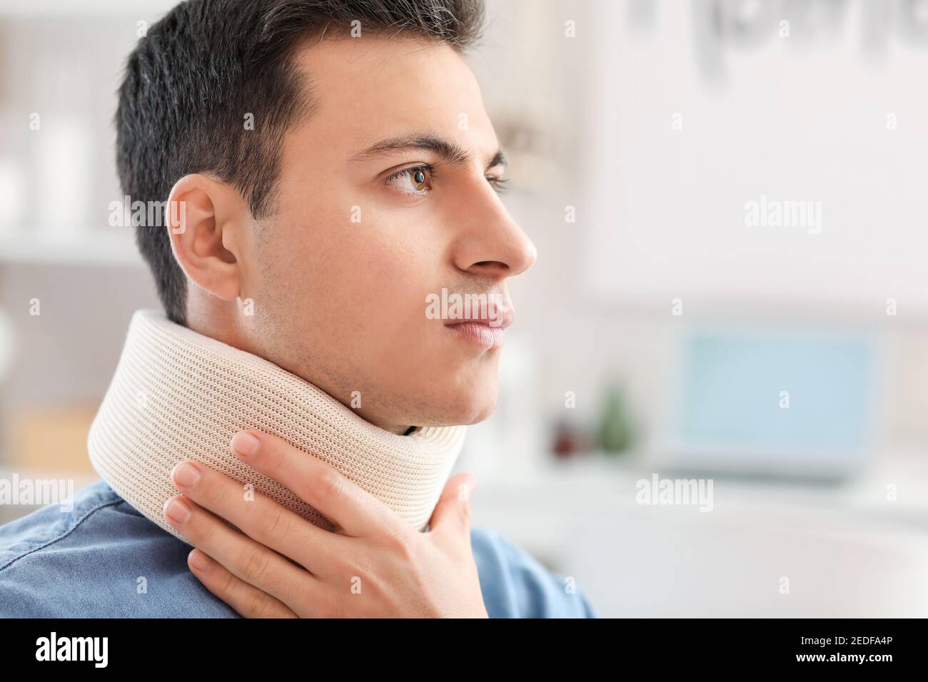 Giovane uomo con collare cervicale sul collo a casa Foto Stock