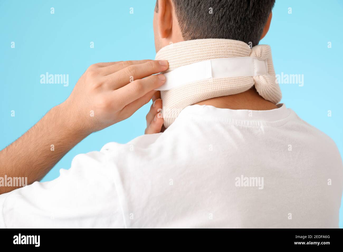 Giovane uomo con colletto cervicale sul collo su sfondo colorato Foto Stock