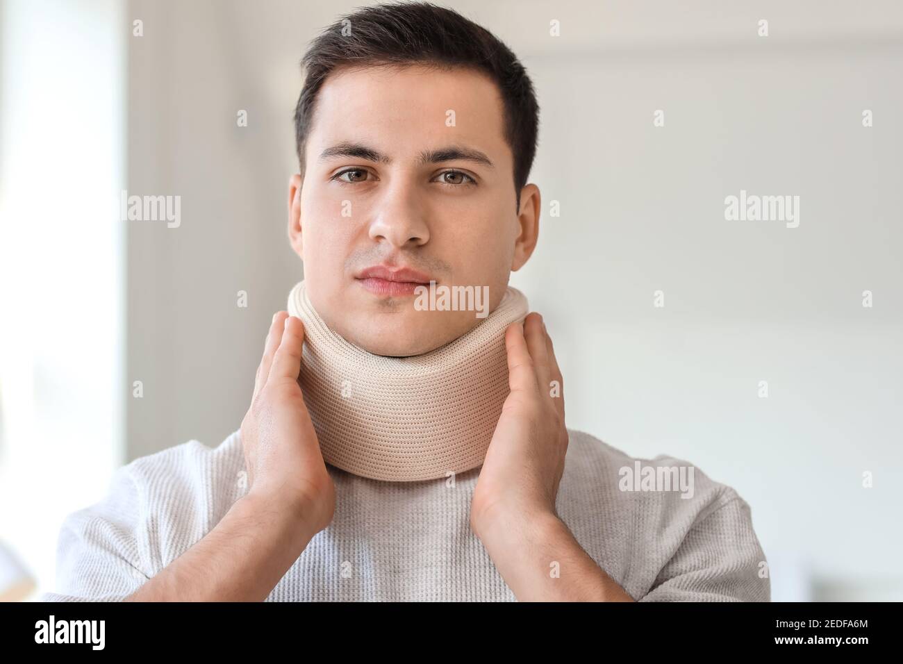 Giovane uomo con collare cervicale sul collo a casa Foto Stock