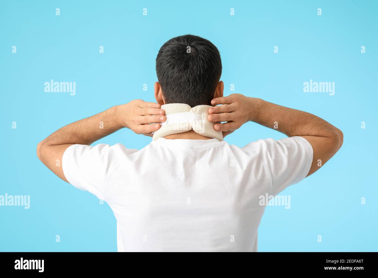 Giovane uomo con colletto cervicale sul collo su sfondo colorato Foto Stock