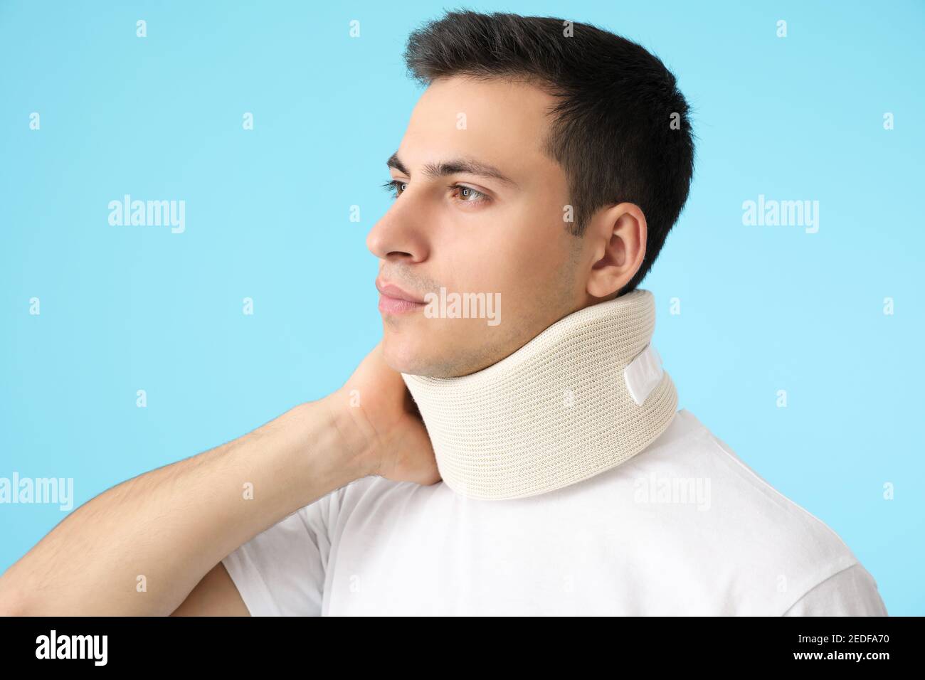 Giovane uomo con colletto cervicale sul collo su sfondo colorato Foto Stock