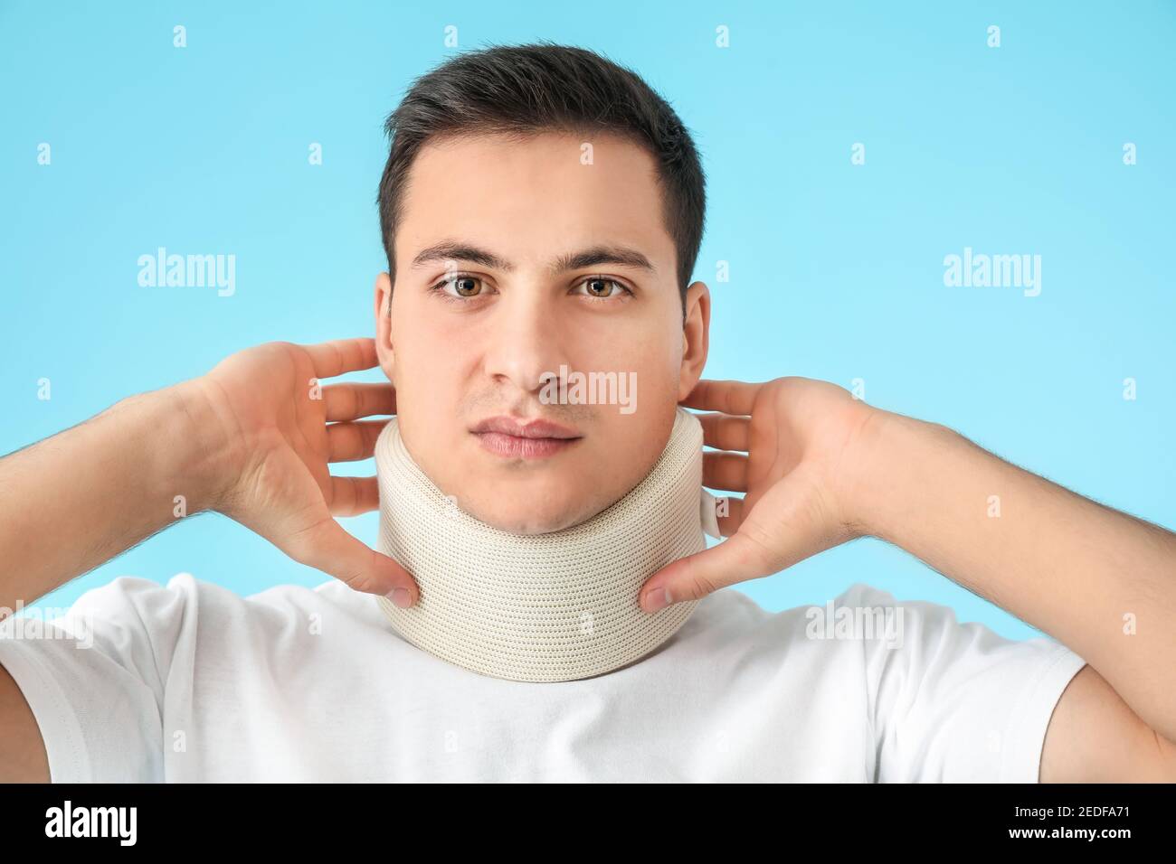 Giovane uomo con colletto cervicale sul collo su sfondo colorato Foto Stock
