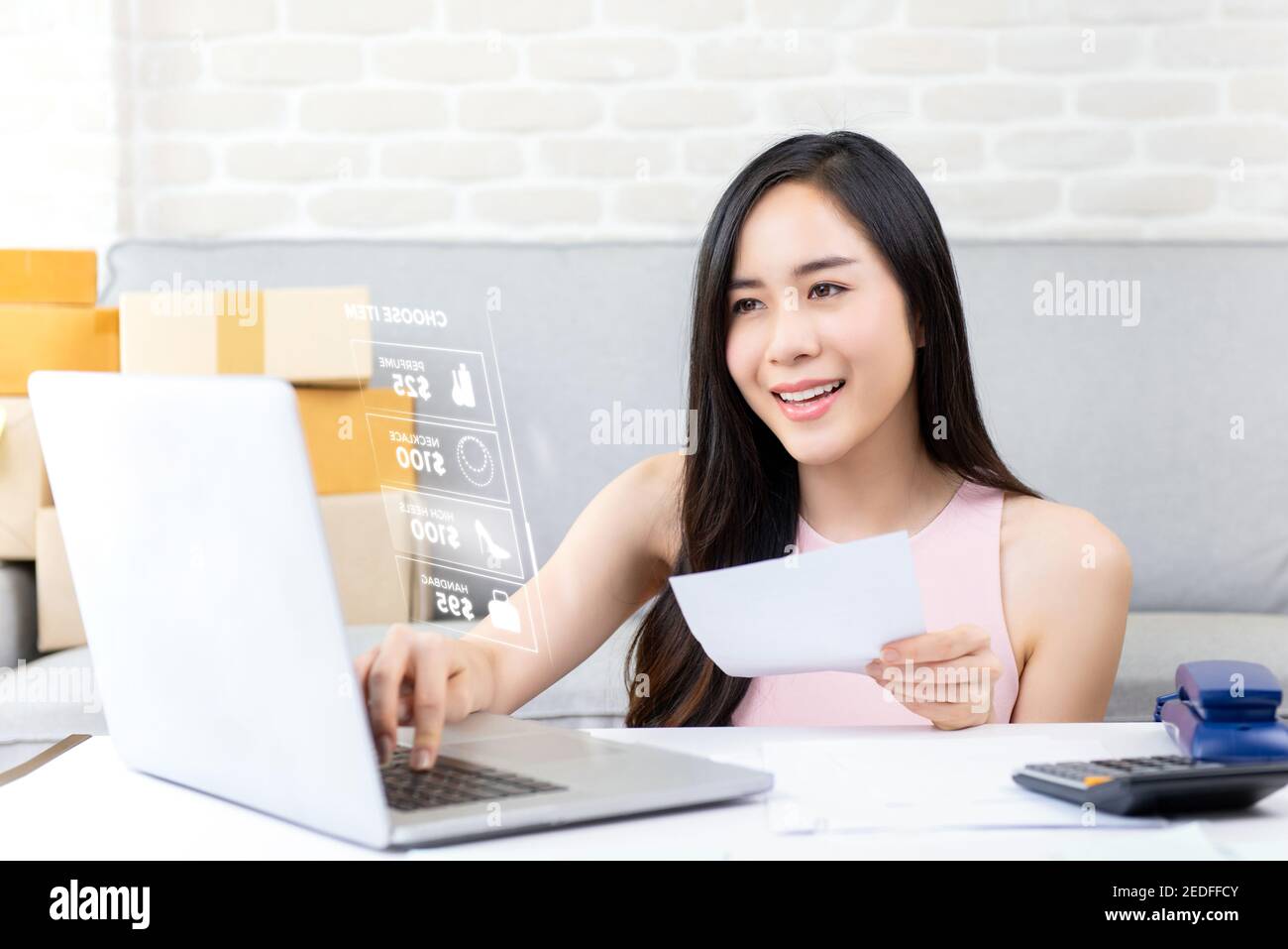 Giovane donna asiatica imprenditore o freelance venditore online che lavora su computer portatile verifica ordine su internet a casa preparazione per consegna Foto Stock