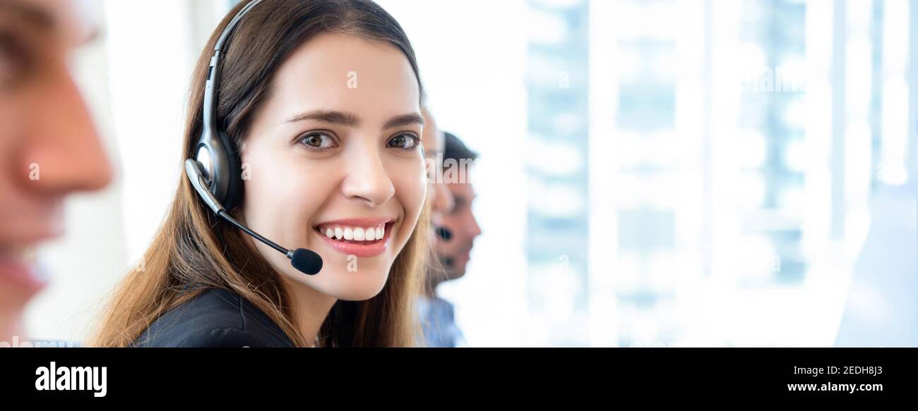 Banner sfondo di sorridente bella donna amichevole che lavora in chiamata centrare l'ufficio con il team come operatori del servizio clienti Foto Stock