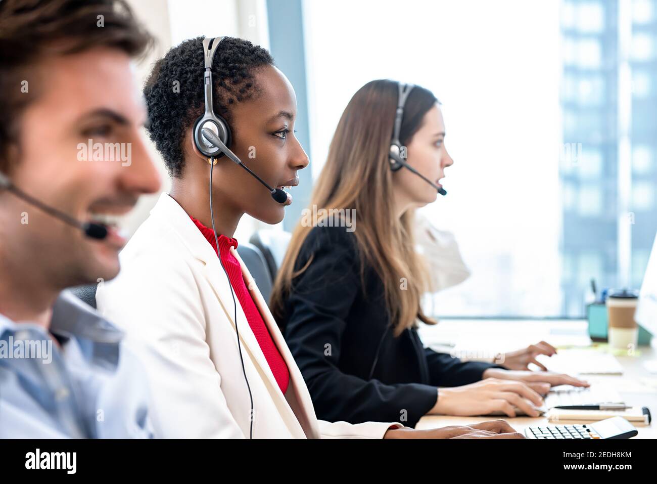 Gruppo di diversi team di telemarketing per il servizio clienti che lavorano in ufficio call center Foto Stock