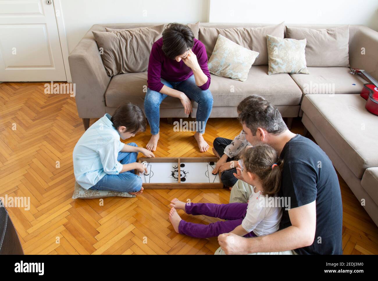 Gioco di gioco di tutta la famiglia. Partita di fratello e sorella. Seduto sul pavimento in mezzo al soggiorno, gioca con tutta la famiglia Foto Stock